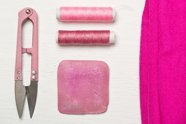 Pink colored flat lay top view sewing tools with texile fabric
