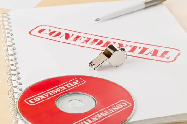 Sifflet chromé sur documents et CD ou DVD avec documents confidentiels — Photo