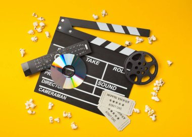 Bekar, siyah, açık film klepti veya dvd film diski, film makarası, patlamış mısır, uzaktan kumanda ve sinema biletleri yukarıdan sarı ya da turuncu arka planda görülüyordu - dijital film, ev sineması ya da film gecesi konsepti