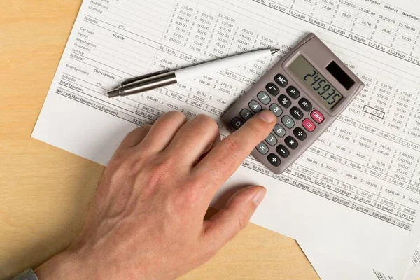 Mężczyzna Korzystający Kalkulatora Kieszonkowego Piórem Tle Arkusza Analizy Finansowej Drewnianym — Zdjęcie stockowe