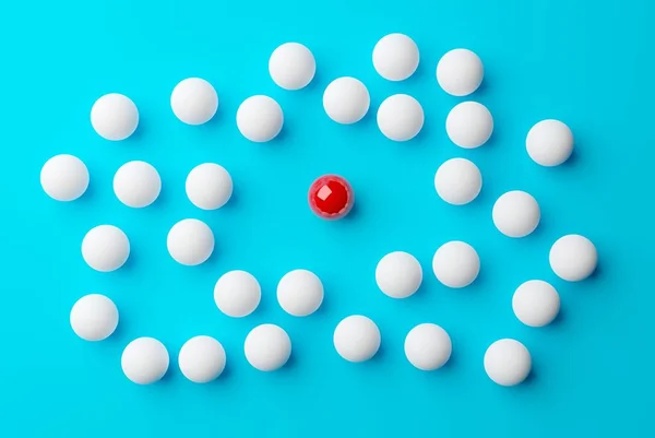 Single red sphere in the middle of group or team of white spheres over blue background, team, leadership or individuality concept, 3d illustration, flat lay top view from above