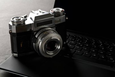 Laptop klavyesindeki analog SLR kamera ofiste siyah masa üzerinde, dijital fotoğrafçılık veya resim işleme konsepti, seçici odaklanma