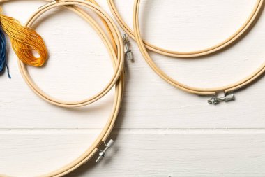 Yuvarlak işlemeli ya da dikişli çerçeve seti beyaz ahşap masa arka planı, düz üst görünüm yukarıdan yatıyordu