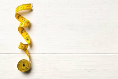 Teyp ölçüm aracı beyaz tahta masa arkaplanı üzerinde fotokopi alanı ile, üst görünüm düz yukarıdan uzanır