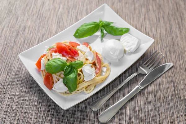 Спагетті зі свіжими помідорами, базиліком, моцарелою та деякими ореганами — стокове фото