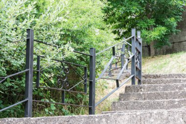 bir tarafa metal korkuluk ve bitki örtüsü ile yukarı gidiyor taş merdiven