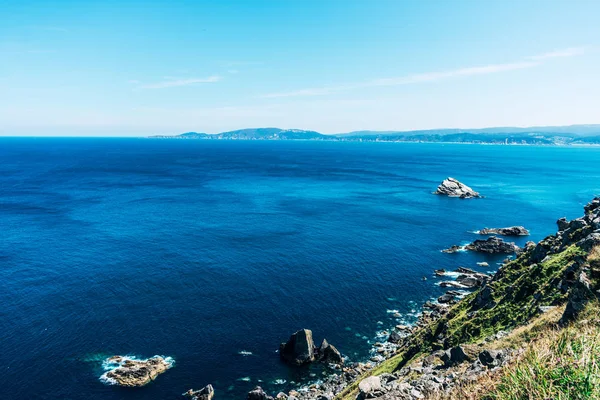 Felsklippe im Ozean mit blauem Wasser und sonnigem Himmel — Stockfoto