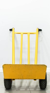 Duvarda duran sarı el arabasının ön görüntüsü