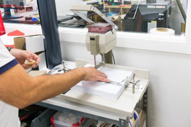 Atölyedeki kağıt yumruklama makinesinde çalışan işçiler