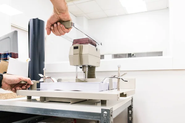 Worker manipulating paper punching machine in workshop — Stock Photo, Image