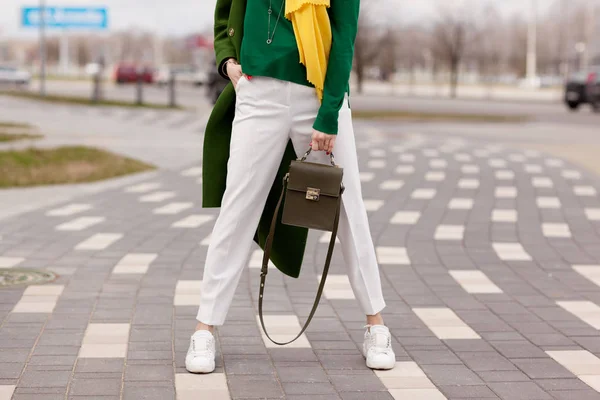 明亮的风格 一个穿着白裤子的年轻女孩 温暖的绿色 Polto 白色运动鞋 黄色围巾 绿色夹克 一个棕色的手提包 — 图库照片