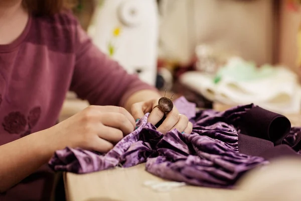 Las manos femeninas que cosen el paño con la aguja en el lugar de trabajo de costura. Vista lateral — Foto de Stock