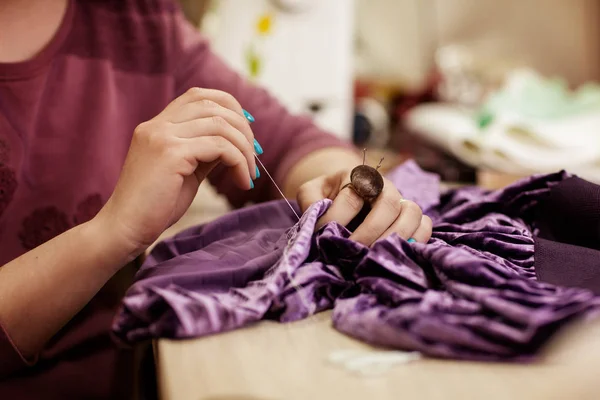 Las manos femeninas que cosen el paño con la aguja en el lugar de trabajo de costura. Vista lateral — Foto de Stock