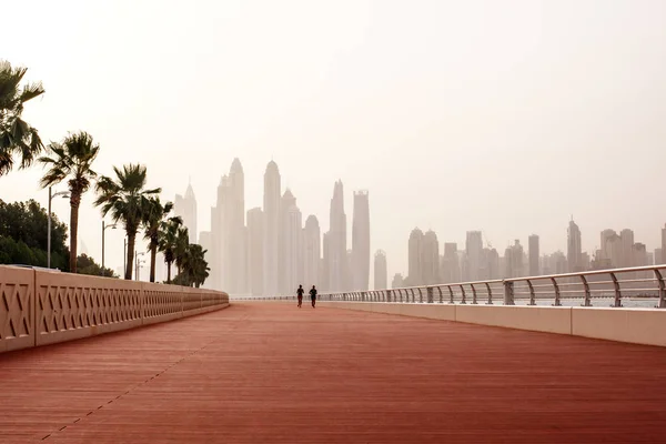 Morning run, a man and a woman run along the road with a beautiful view of Dubai. UAE