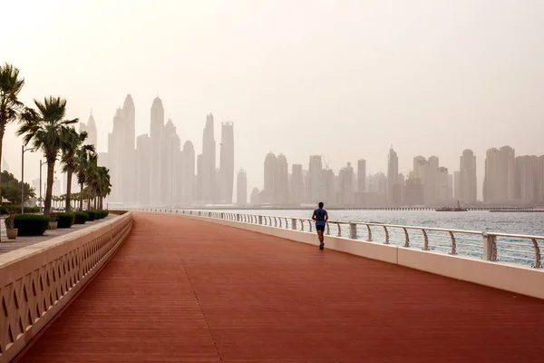 Morning run, a man runs along the road with a beautiful view of Dubai. UAE