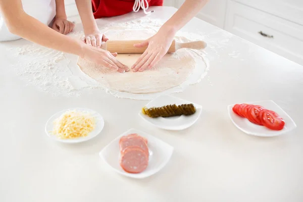 Дитячі руки відкотити піцу тісто на білому столі. Хаві — стокове фото