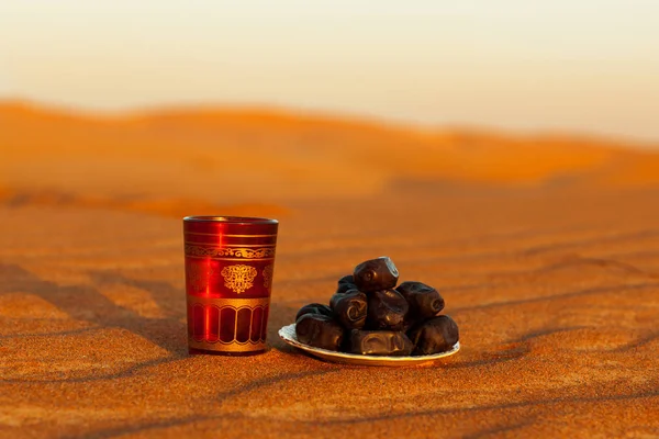ラマダン・カリーム砂漠の美しい夕日の太陽の背景に水のガラスとプレートの日付です — ストック写真