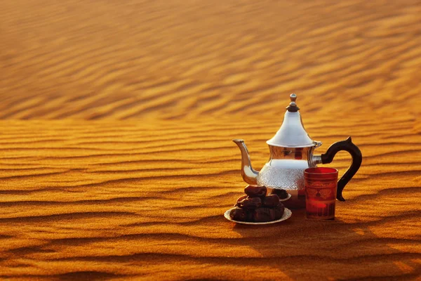 Tetera árabe, taza y dátiles en el desierto en una hermosa puesta de sol que simboliza el Ramadán —  Fotos de Stock