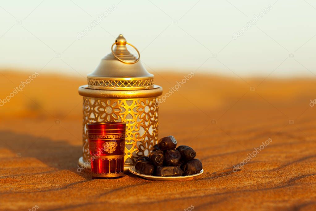 Lantern, cup and dates in the desert at a beautiful sunset, symbolizing Ramadan