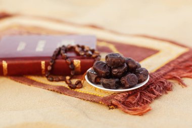 Kur'an-ı Kerim kitabı, hurma ve tespihler çöldeki dua minderinin üzerine güzelce serilir. Ramazan Kareem