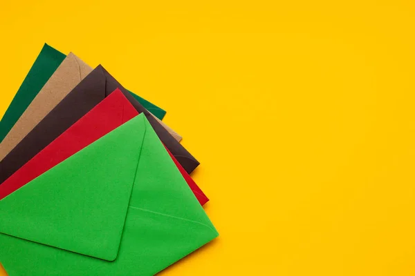 Enveloppe rouge, marron, verte sur fond jaune, avec espace pour le texte, vue du dessus — Photo