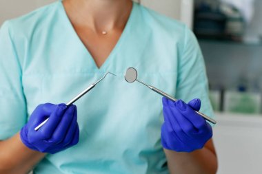 Kadın diş hekimi derzhit profesyonel diş hekimi araçları diş ofisinde, ayna ve kavisli cımbız, hijyen ve diş sağlığı imajı