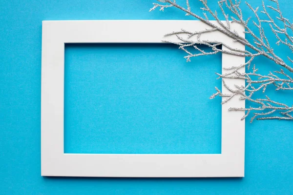 White frame, silver branch on a blue background. New year, holiday, decoration. With place for text. View from above — Stock Photo, Image