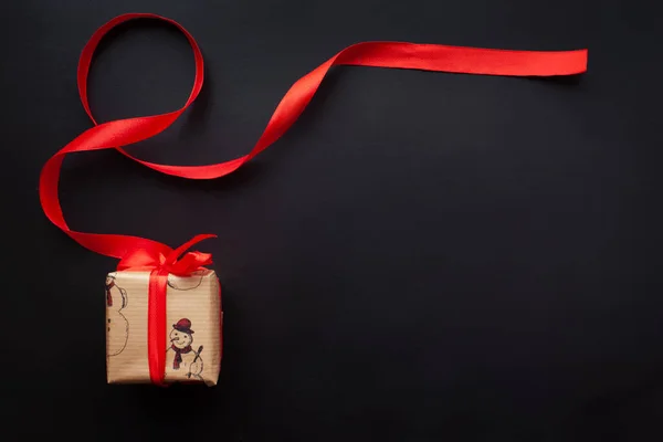 Regalos de Navidad envueltos en una cinta roja sobre un fondo negro. Año nuevo, vacaciones, decoración. Con lugar para el texto. Vista desde arriba — Foto de Stock