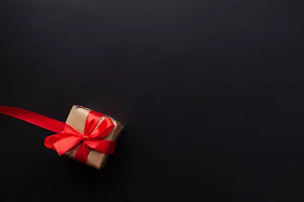 Regalos de Navidad envueltos en una cinta roja sobre un fondo negro. Año nuevo, vacaciones, decoración. Con lugar para el texto. Vista desde arriba — Foto de Stock