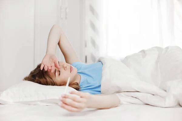 生病时一个漂亮的女孩躺在床上 量体温 发烧期间身体不好 案文之间的位置 — 图库照片