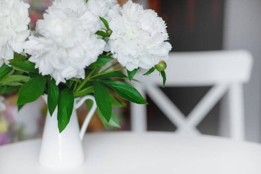 Güzel bir buket beyaz şakayığı kapayın ve açık renkli bir masanın üzerinde durun.