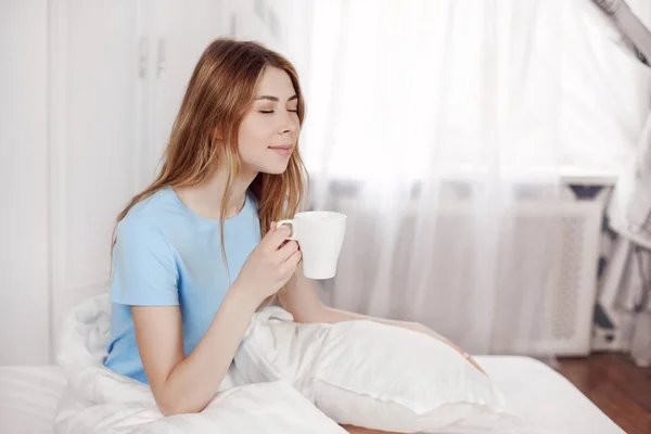 아름다운 아가씨가 침대에 커피를 마시고 있어요 음료를 아침을 즐기고 — 스톡 사진