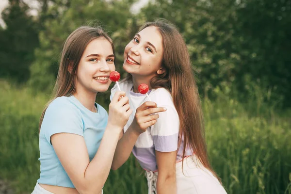 Dvě Šťastné Dospívající Dívky Drží Jasně Červené Lízátko Sladkosti — Stock fotografie
