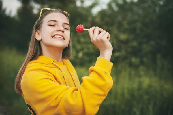 Uma Menina Sorridente Uma Camisola Amarela Brilhante Segura Chupa Chupa — Fotografia de Stock