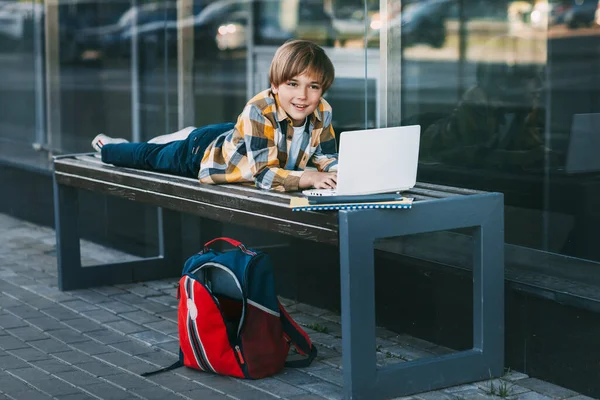 Cheerful Boy Lying Wooden Bench Working Laptop Next Backpack Student — Stock Photo, Image