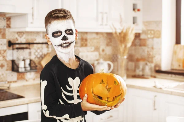 Felice ragazzo vestito come un uomo morto ridendo e tenendo Jack zucca lanterna mentre celebra Halloween — Foto Stock