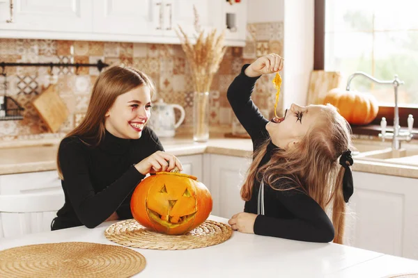 I bambini felici festeggiano Halloween in cucina in costume e trucco con lanterna di zucca, si divertono e ridono — Foto Stock