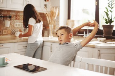 Yorgun bir çocuk evdeki internet derslerinden sonra kendini yukarı çekiyor, kız kardeşi de ona yardım ediyor. Uzaktan öğrenme, çevrimiçi eğitim, evde eğitim kavramı