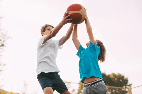 십 대 소년 두 명이 운동장에서 농구를 한다. 선수들은 경기중에 공을 놓고 싸웁니다. 건강 한 생활, 스포츠 — 스톡 사진