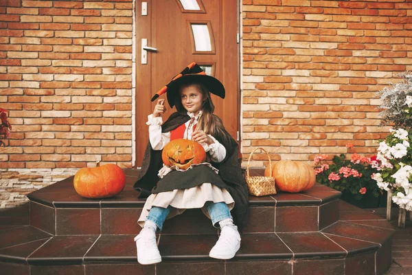 Klein meisje verkleed als een fee met een lantaarn jack zit op de trap in de buurt van haar huis tijdens de Halloween viering — Stockfoto