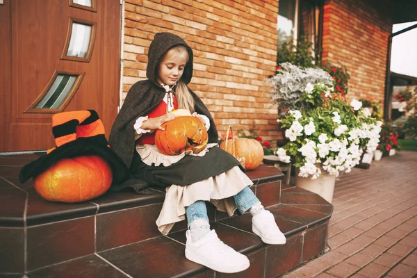 Bambina vestita come una fata con un cric lanterna siede sui gradini vicino a casa sua durante la celebrazione di Halloween — Foto Stock