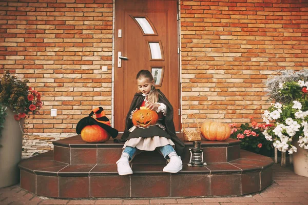 Κοριτσάκι ντυμένο σαν νεράιδα με ένα φανάρι, κάθεται στα σκαλιά κοντά στο σπίτι της κατά τη διάρκεια του εορτασμού του Χάλογουιν. — Φωτογραφία Αρχείου