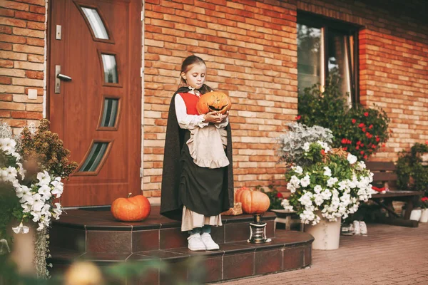 Bambina vestita come una fata con una lanterna jack si erge sui gradini vicino a casa sua durante la celebrazione di Halloween — Foto Stock