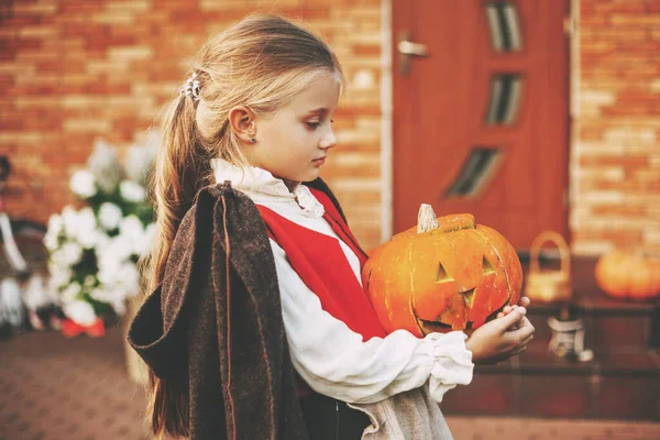 Mooi klein meisje gekleed als een fee met een pompoen in haar handen tijdens de viering van Halloween — Stockfoto