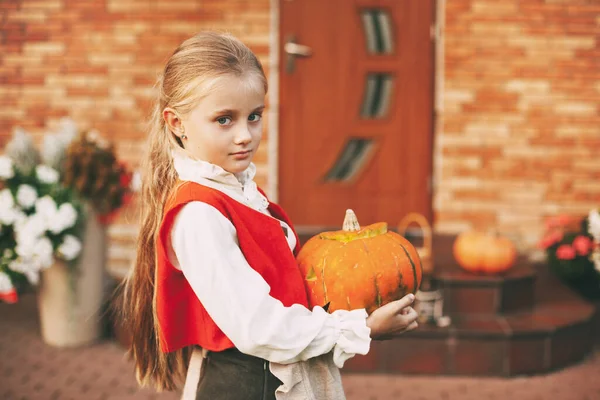 Mooi klein meisje gekleed als een fee met een pompoen in haar handen tijdens de viering van Halloween — Stockfoto