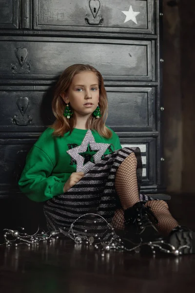Portrét krásné holčičky v módní novoroční image, v zelené mikině a drží dárek. — Stock fotografie