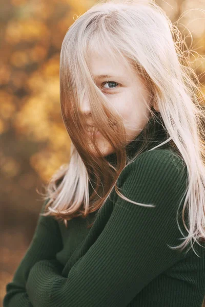 Retrato de uma linda adolescente com cabelo loiro e olhos azuis com um sorriso no rosto em um parque de outono — Fotografia de Stock