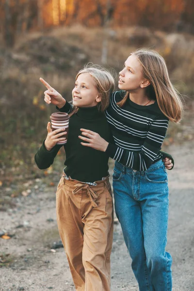 Obě sestry se vrací ze školy a povídají si, když projíždějí podzimním parkem pod širým nebem. — Stock fotografie