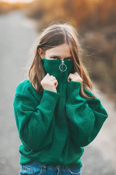 Menina adolescente bonita com cabelo loiro e olhos azuis em uma camisola verde quente em um parque de outono. — Fotografia de Stock