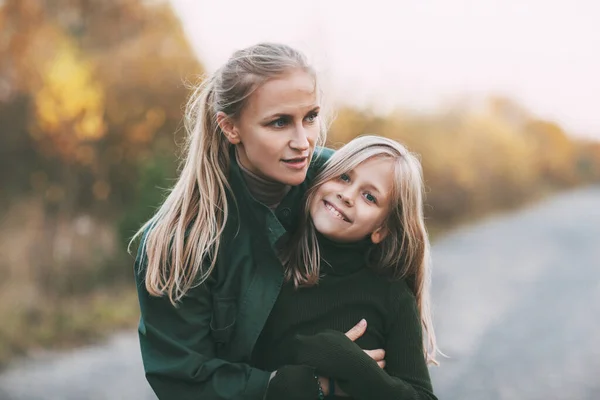 Портрет щасливої зрілої мами і її блондинки маленька дочка обіймає і сміється під час прогулянки в осінньому парку на відкритому повітрі . — стокове фото